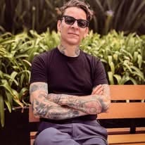 Photo of Jhon Rodriguez sitting on a bench with sunglasses on