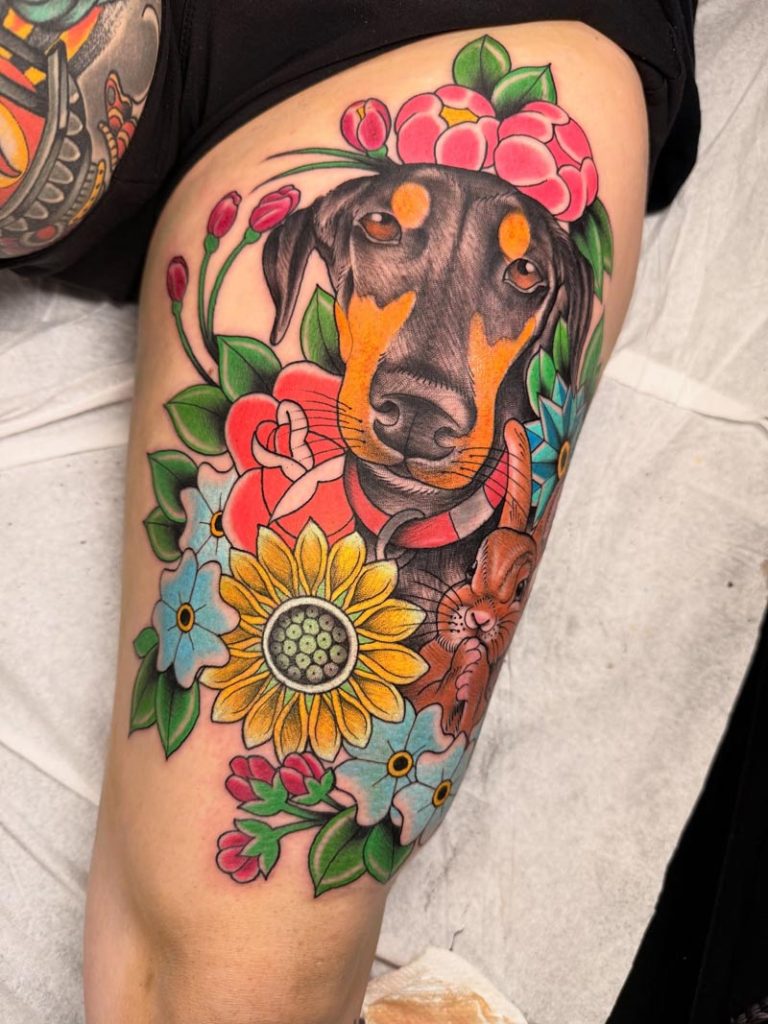 Colorful dog and flowers thigh tattoo