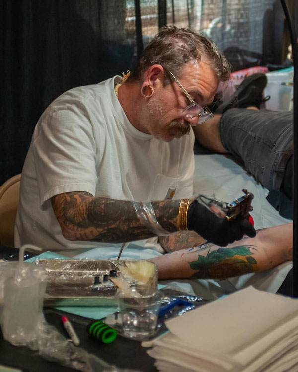 Male Tattoo Artist tattooing an arm